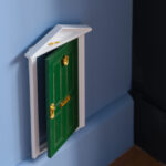 Miniature green door in a blue wall at MIRO Rooms Riga.